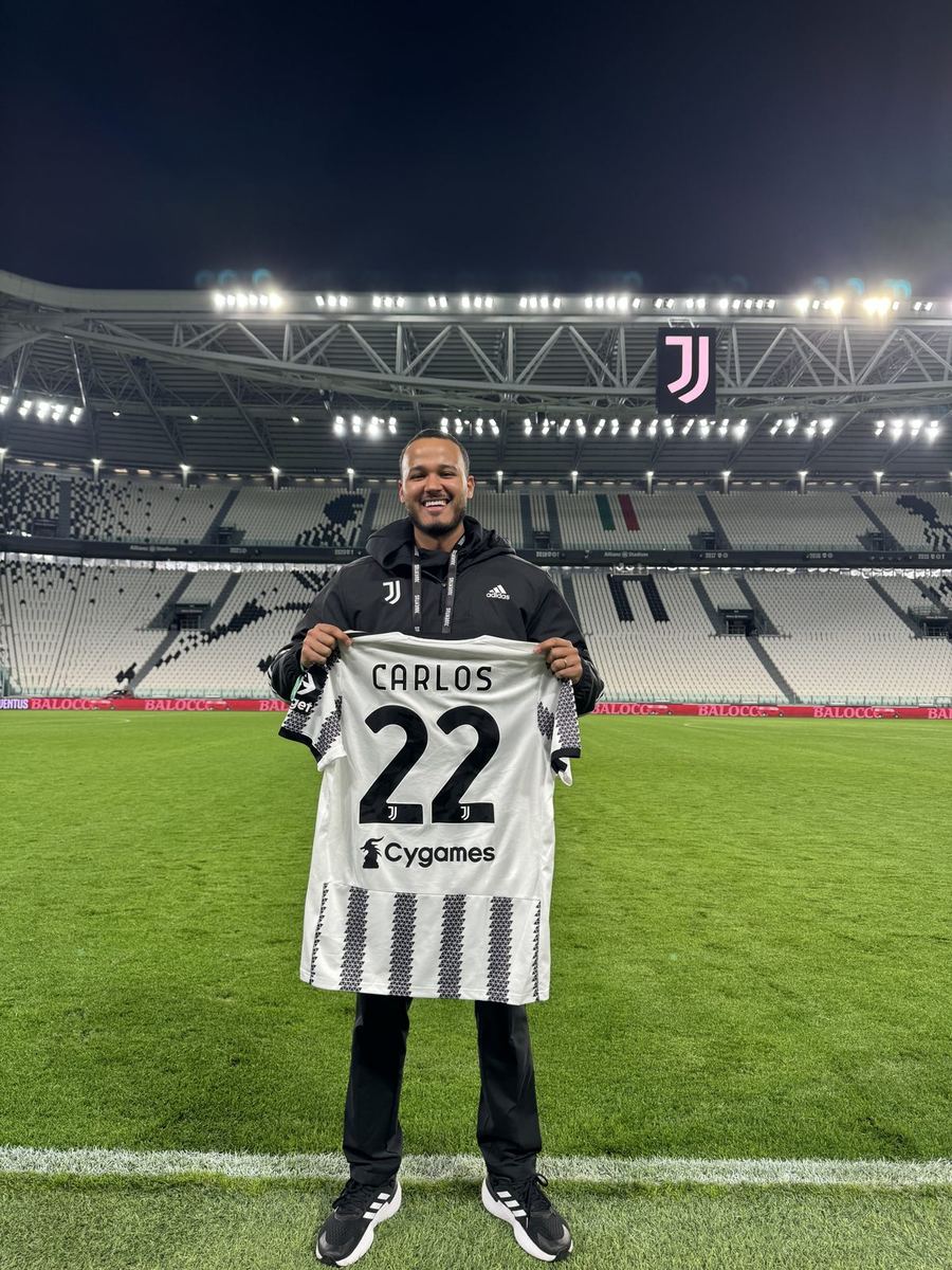 Carlos holding a Juventus shirt with his name at Allianz Stadium